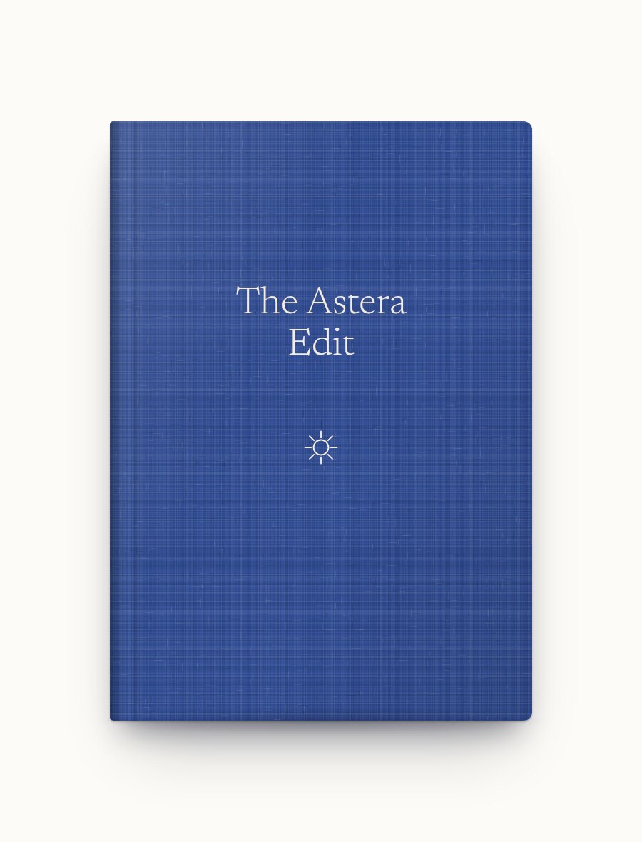The Astera Edit closed: a blue linen-weave hardcover with the title and a small sun